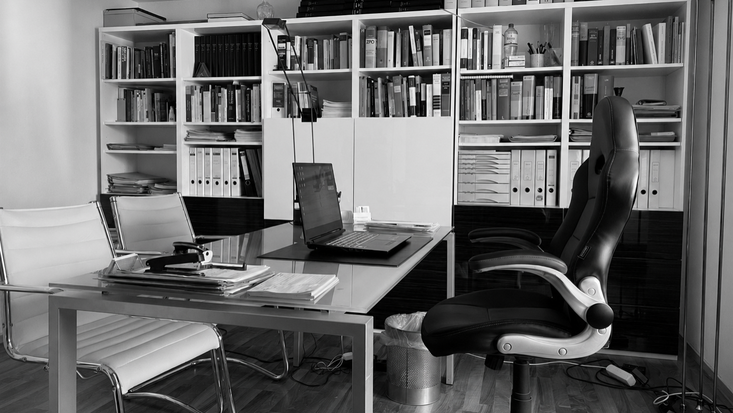Ein schwarz-weißes Bild eines gut bestückten Arbeitszimmers mit Bücherregalen und einem Schreibtisch.